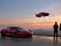 Le nouveau Tesla Roadster face aux régulateurs américains Une Tesla Roadster rouge au sol et une autre volant dans le ciel au coucher du soleil face à deux personnes en costume.