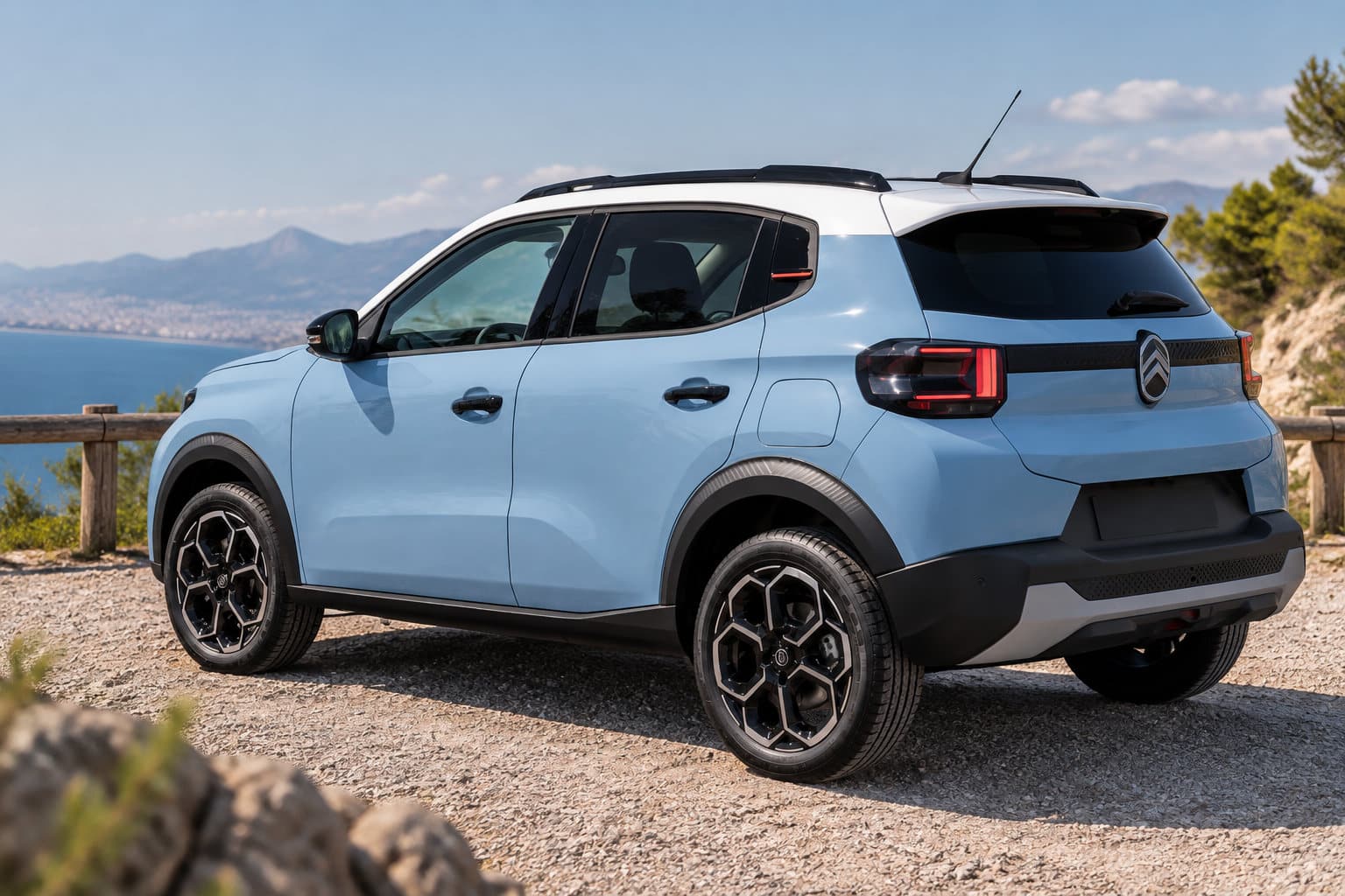 Un SUV bleu clair est garé sur un chemin rocailleux au bord d’un lac, avec des montagnes à l’arrière-plan.